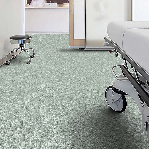 Hospital room with a bed and stool on a green carpet