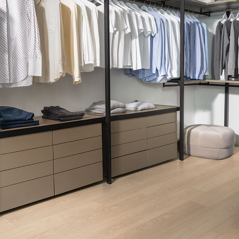 Modern wardrobe with hanging clothes and drawers in a well-lit room.