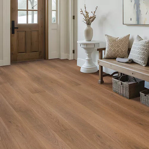 Brown wood-look plank flooring shown in a bright, modern entryway with a wooden bench, white side table, and a wooden front door.