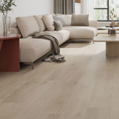 Light oak wood plank flooring shown in a modern, sunlit living room with a beige sectional sofa, wooden slat wall, and gray armchair.