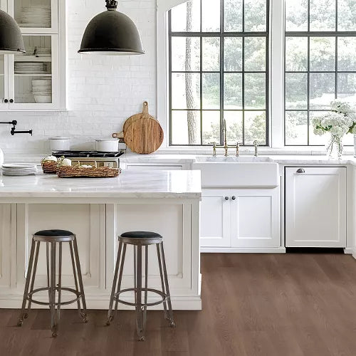 Modern kitchen with white cabinets, marble island, and black pendant lights.