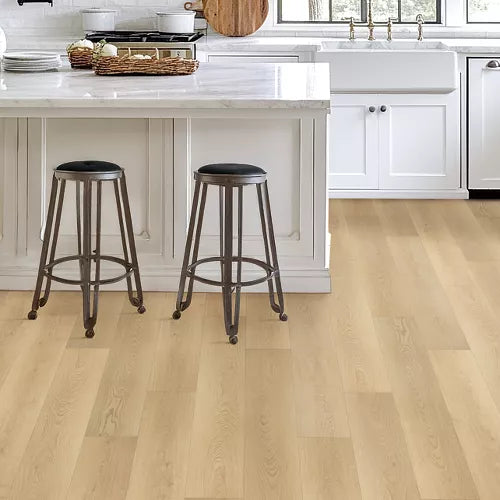 Light oak hardwood flooring in a bright, modern kitchen with white cabinets, a farmhouse sink, and two dark metal bar stools.