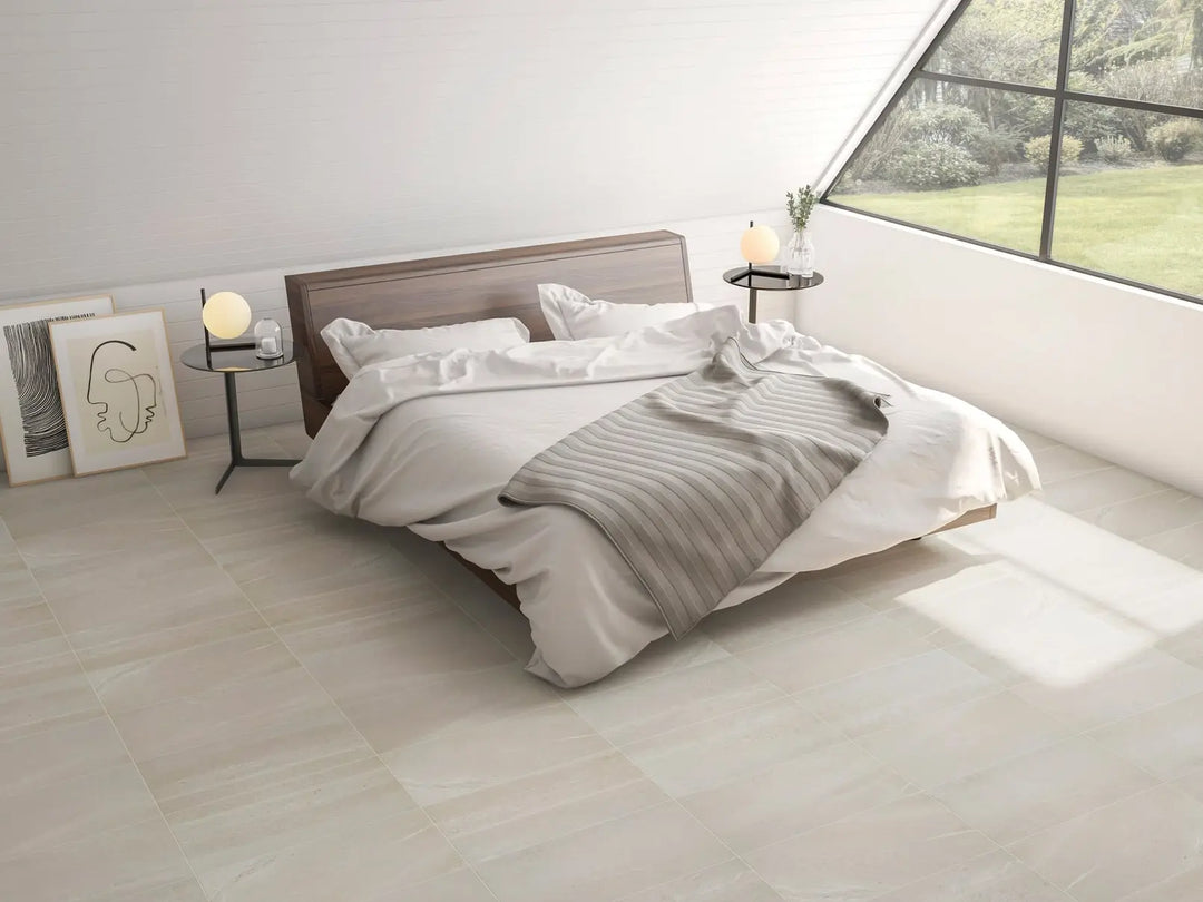 Neatly made bed with white and gray bedding in a bright bedroom.