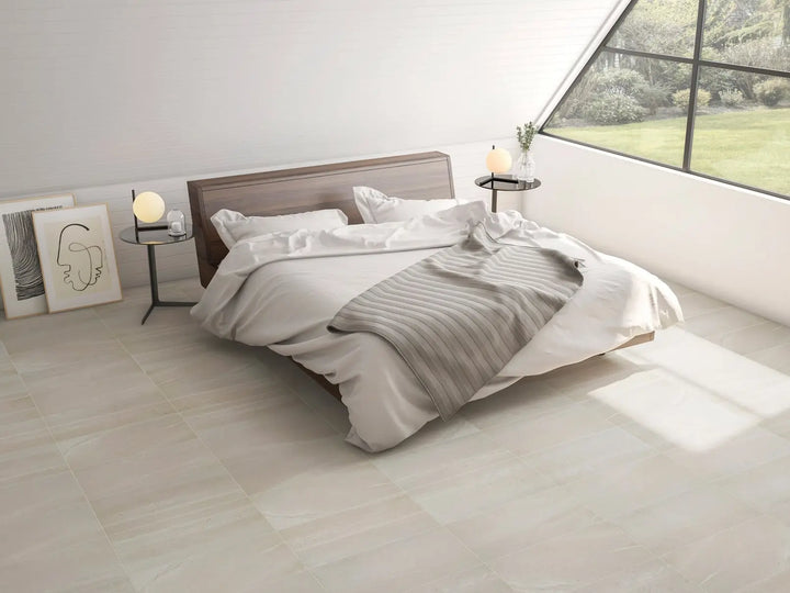Neatly made bed with white and gray bedding in a bright bedroom.