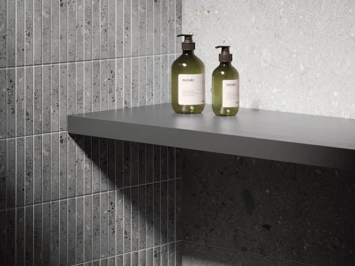 Two bottles on a gray shelf against tiled walls
