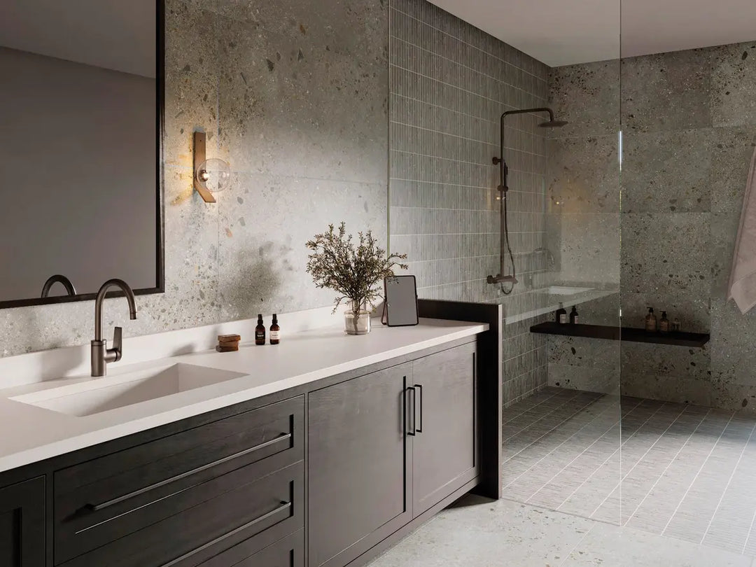 Modern bathroom with dark wooden vanity, white countertop, and gray tiled walls.
