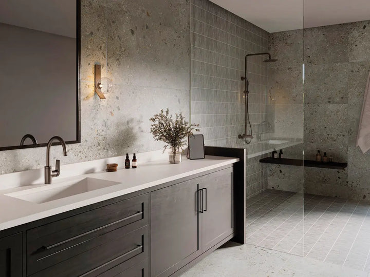 Modern bathroom with dark wooden vanity, white countertop, and gray tiled walls.