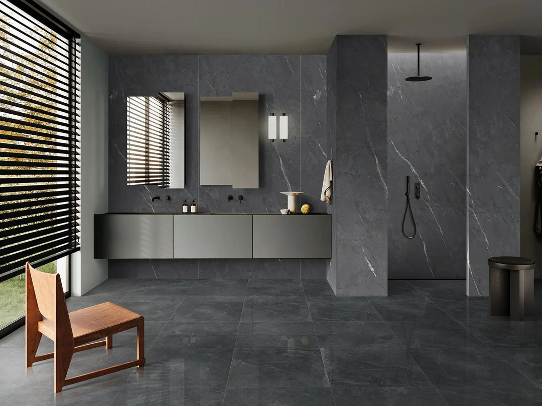 Modern bathroom with gray tiles, a wooden chair, and a shower area.
