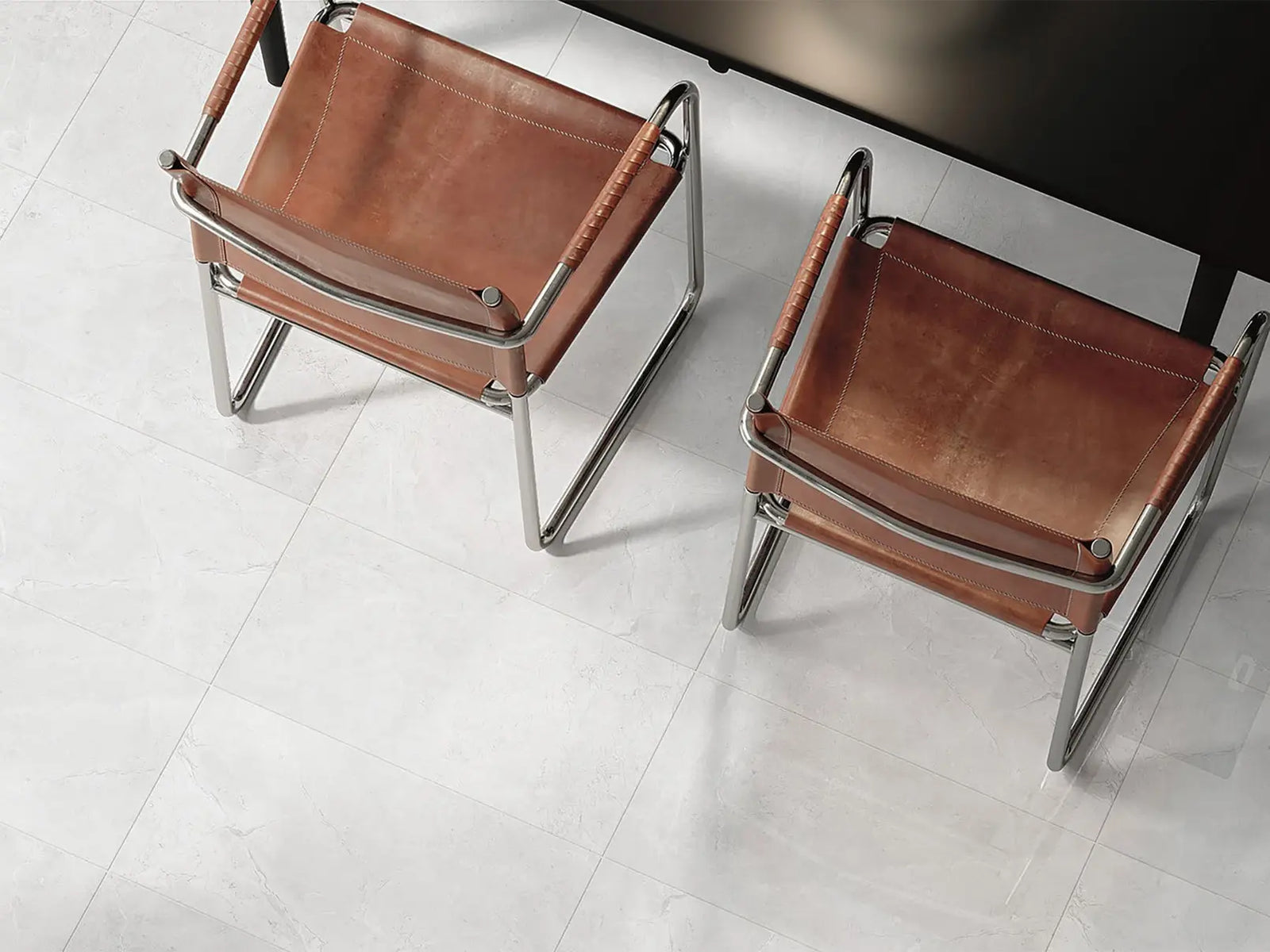 Two brown leather chairs with metal frames on a white floor.