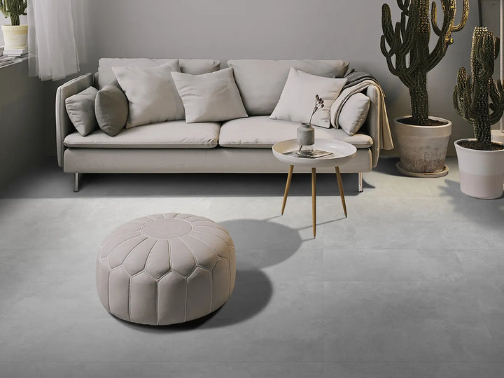Modern living room with a gray sofa, ottoman, and potted plants.