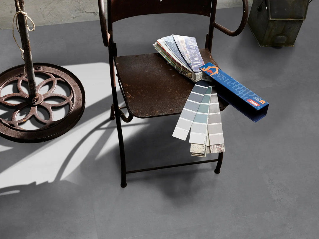 Color swatches and a paint sample book on an iron chair against a gray floor.