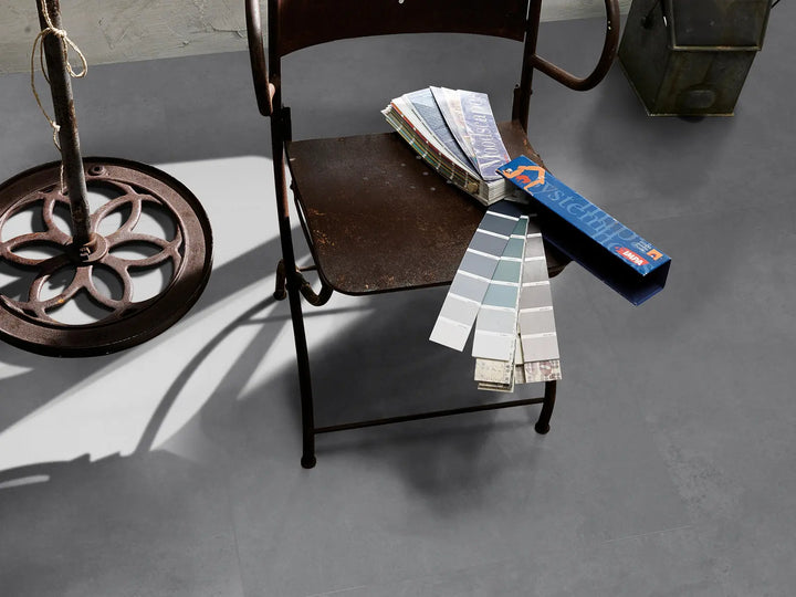 Color swatches and a paint sample book on an iron chair against a gray floor.