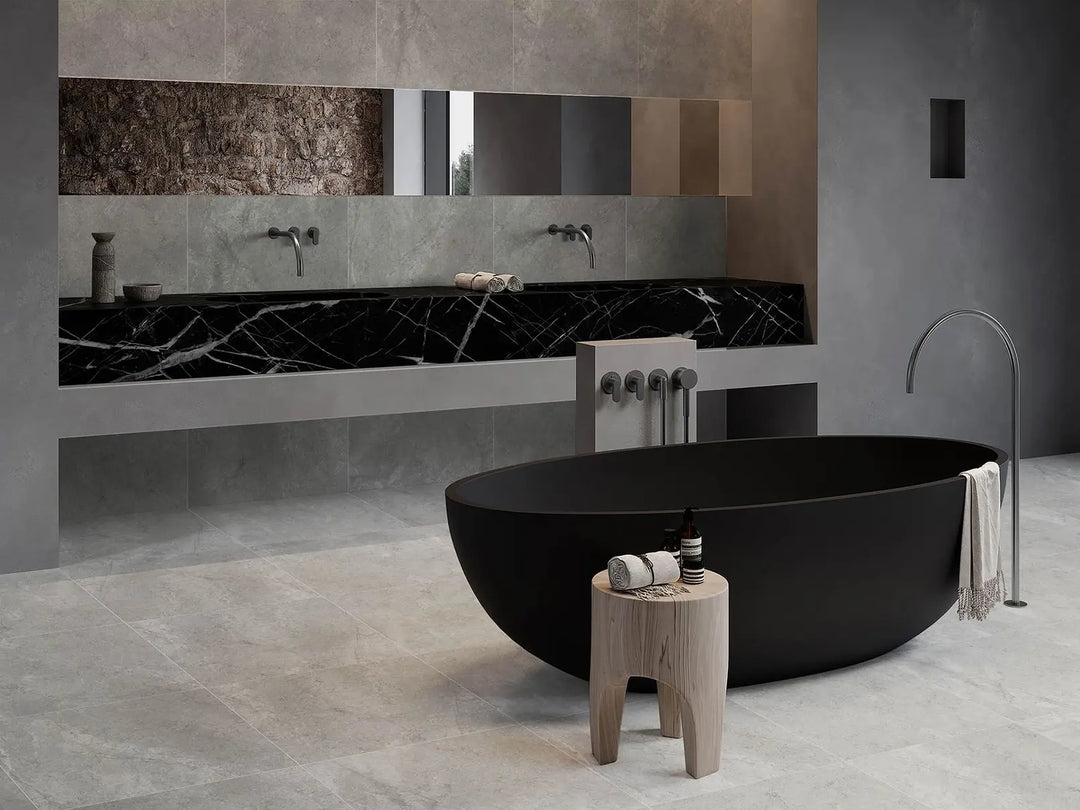 Modern bathroom with a black freestanding bathtub, wooden stool, and marble wall.