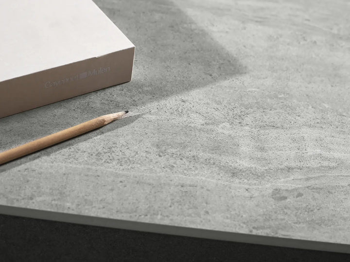 Gray concrete surface with a pencil and a box labeled 'Cemento' on a matching gray background.