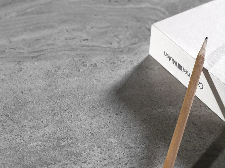 Pencil on a textured gray surface with a white box labeled 'Muller' in the background.