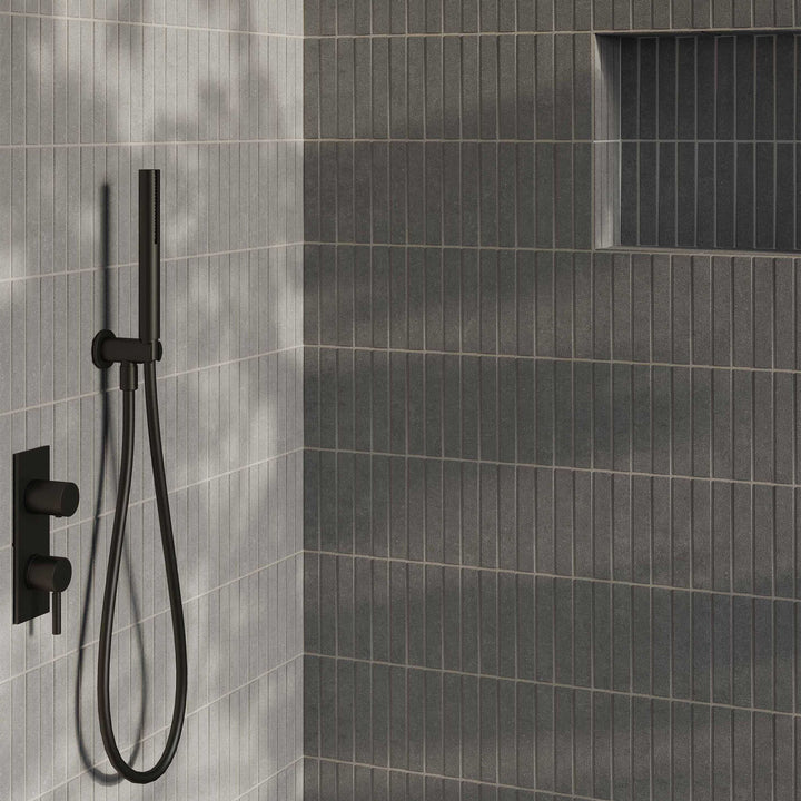 Black shower head and control valve mounted on a gray tiled wall.