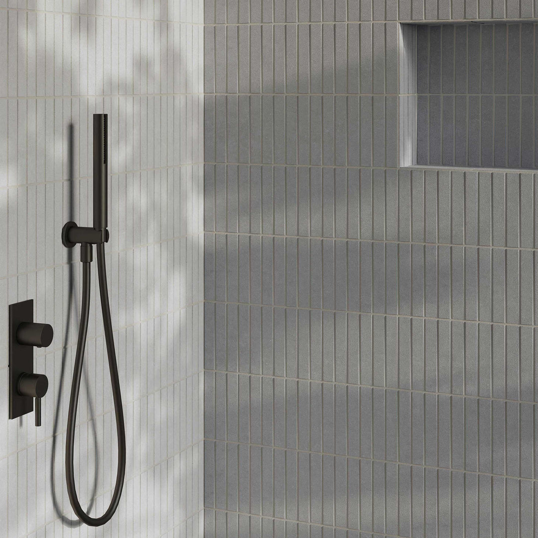 Black shower head and control valve mounted on a gray tiled wall.