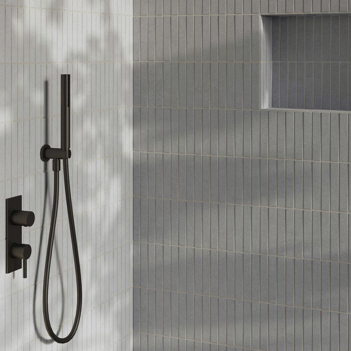 Black shower head and control valve mounted on a gray tiled wall.
