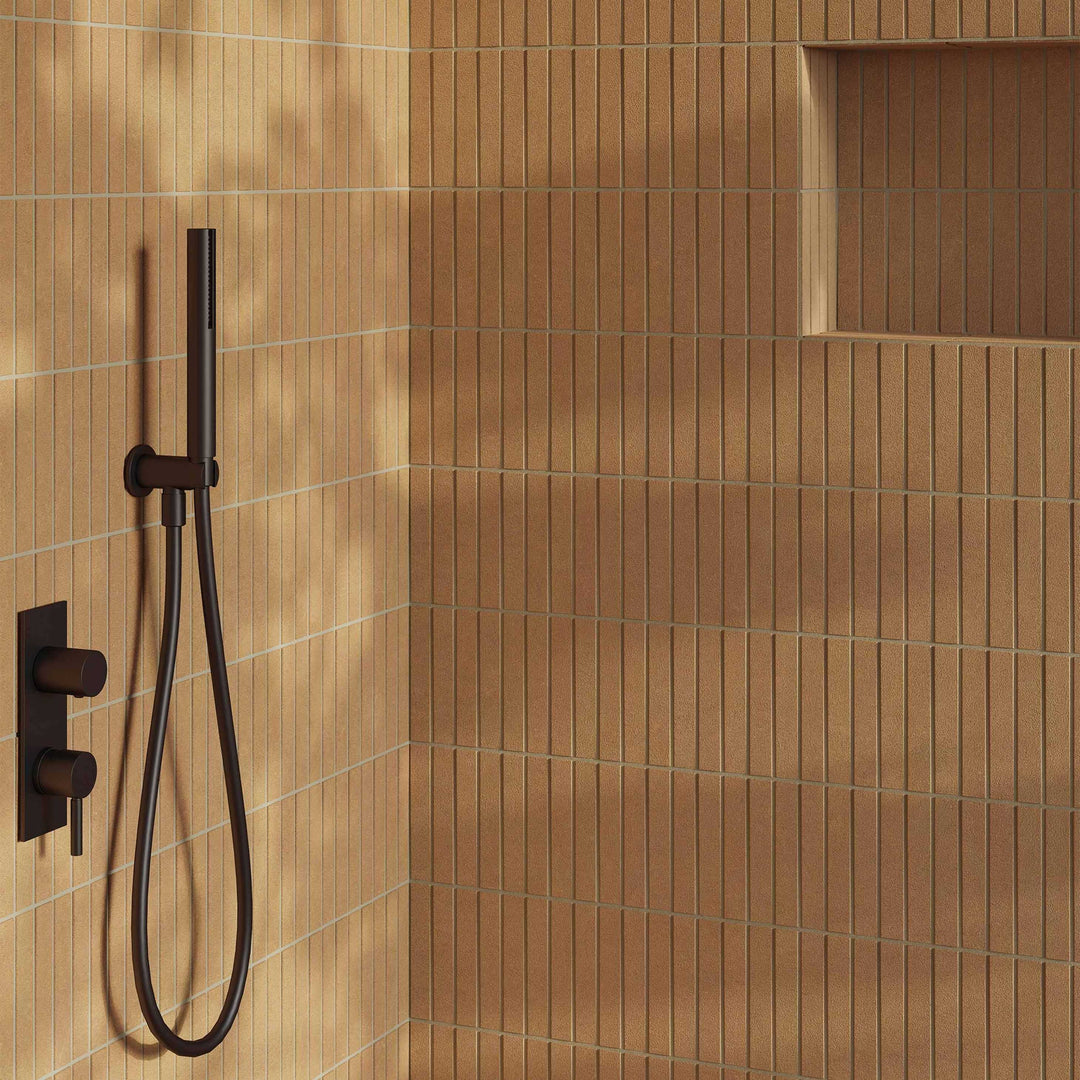 Brown tiled shower with a handheld shower head and control valve.