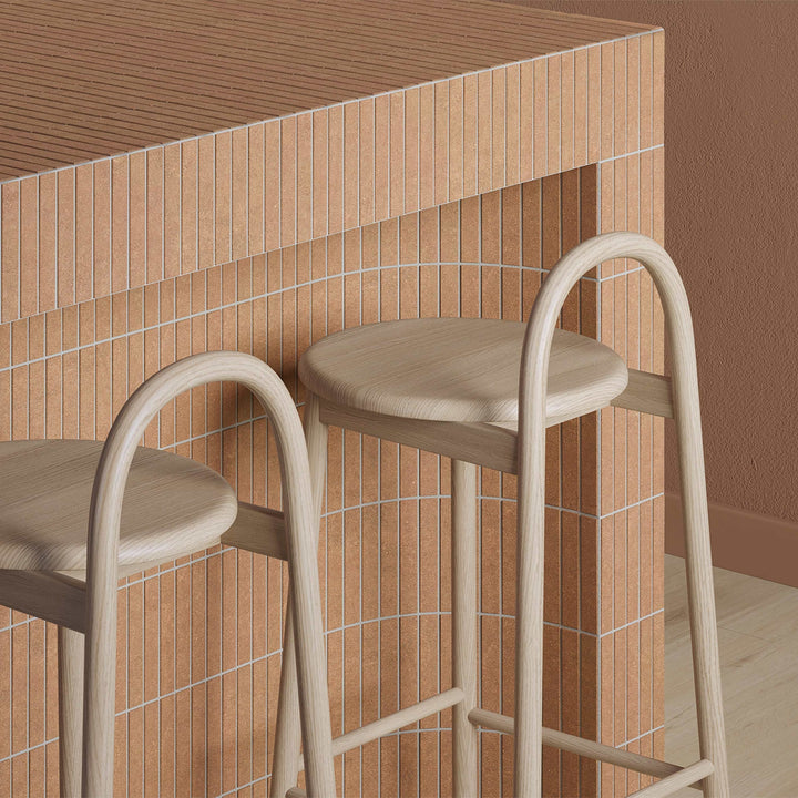 Two bar stools with beige seats and frames against a tiled wall.