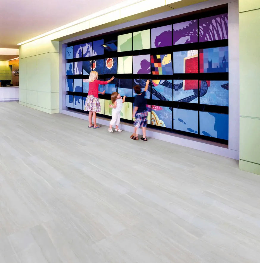 Three children interacting with a large digital display wall in a modern indoor setting.