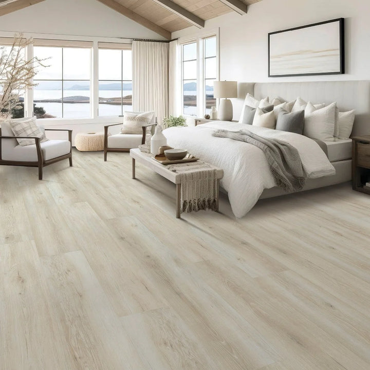 Modern bedroom with wooden flooring, bed, and seating area.