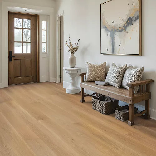 Light oak hardwood flooring in a bright, modern entryway featuring a wooden bench with patterned throw pillows, a white side table with a vase, and a framed abstract painting on the wall.