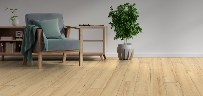 Modern living room with a gray armchair, wooden side table, and potted plant on a light wood floor.