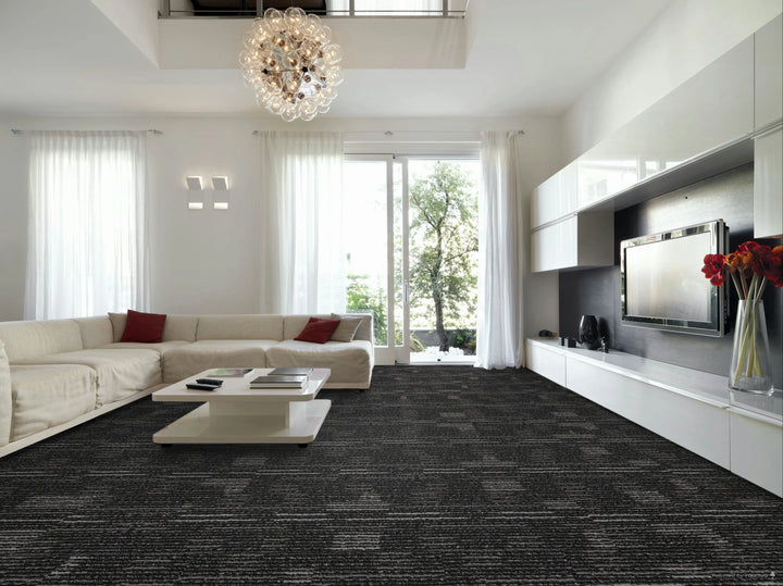 Modern living room with a gray carpet, white walls, and a large window.