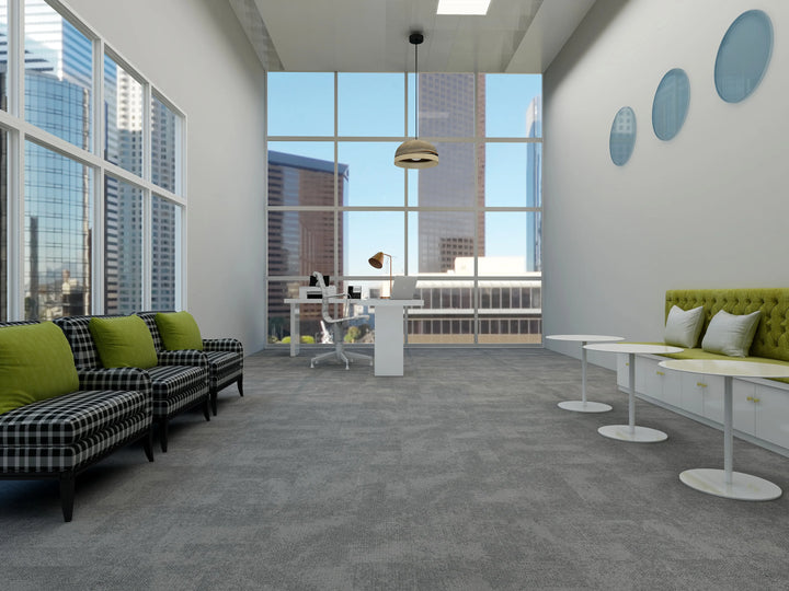 Modern office space with large windows, green sofas, and a desk.