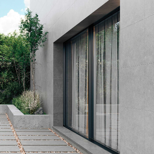 Modern building exterior with large glass windows and a wooden pathway.