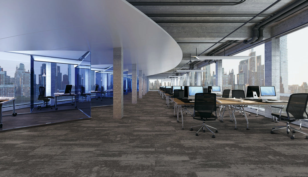 Modern office space with desks, chairs, and large windows overlooking a cityscape.