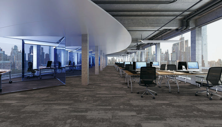 Modern office space with desks, chairs, and large windows overlooking a cityscape.