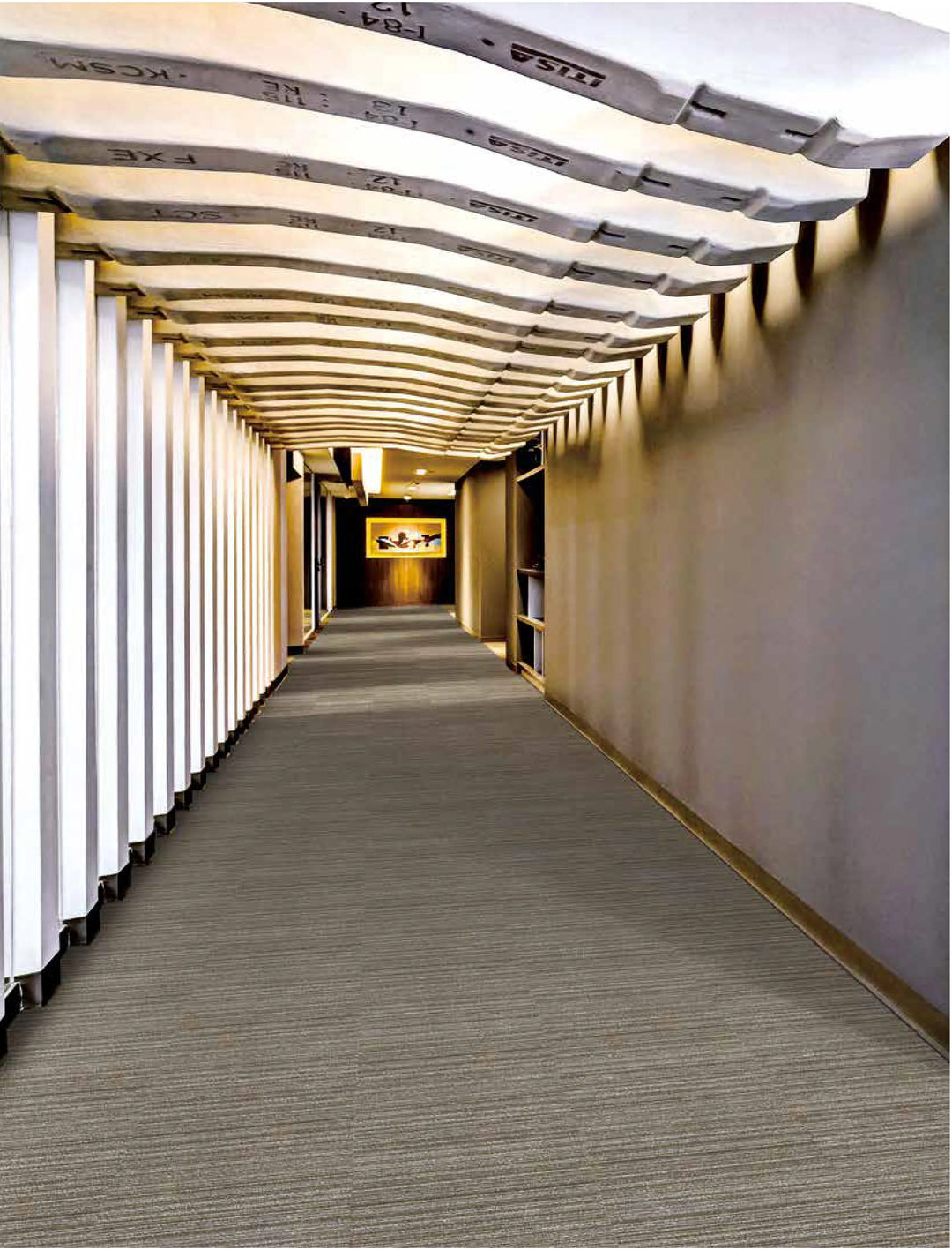 Long, narrow hallway with a patterned ceiling and carpeted floor.