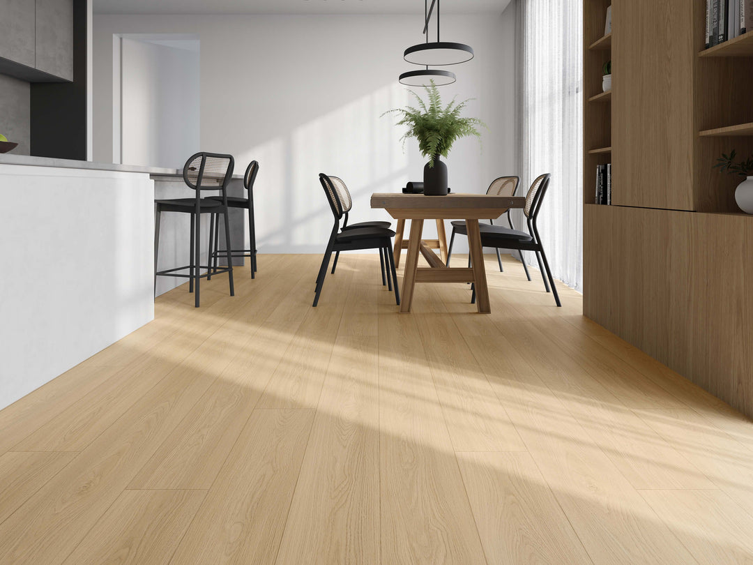 Light oak laminate flooring in a modern dining room setting, shown from a low angle with natural sunlight casting soft shadows across the floor. Advanced Flooring