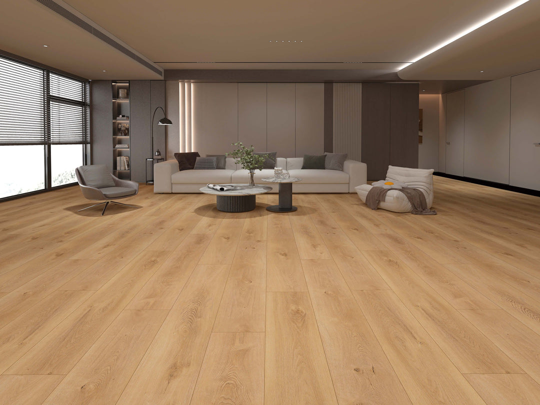 Light oak laminate plank flooring shown in a modern, minimalist living room with a white sofa, gray armchair, and neutral-toned walls. Available at Advanced Flooring.