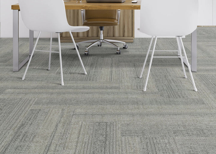 Gray carpeted floor with office chairs and desk in the background