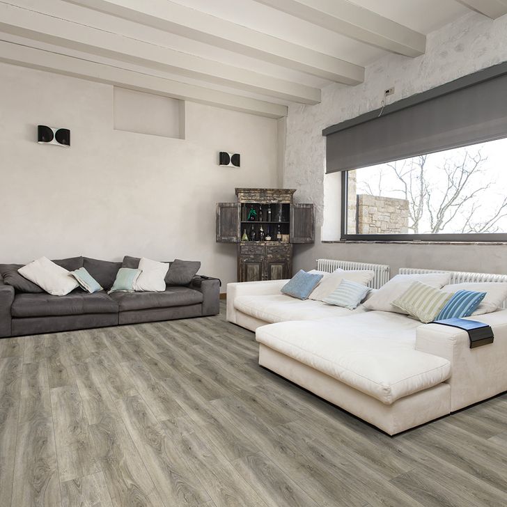 Modern living room with gray and white sofas, a TV stand, and large windows.