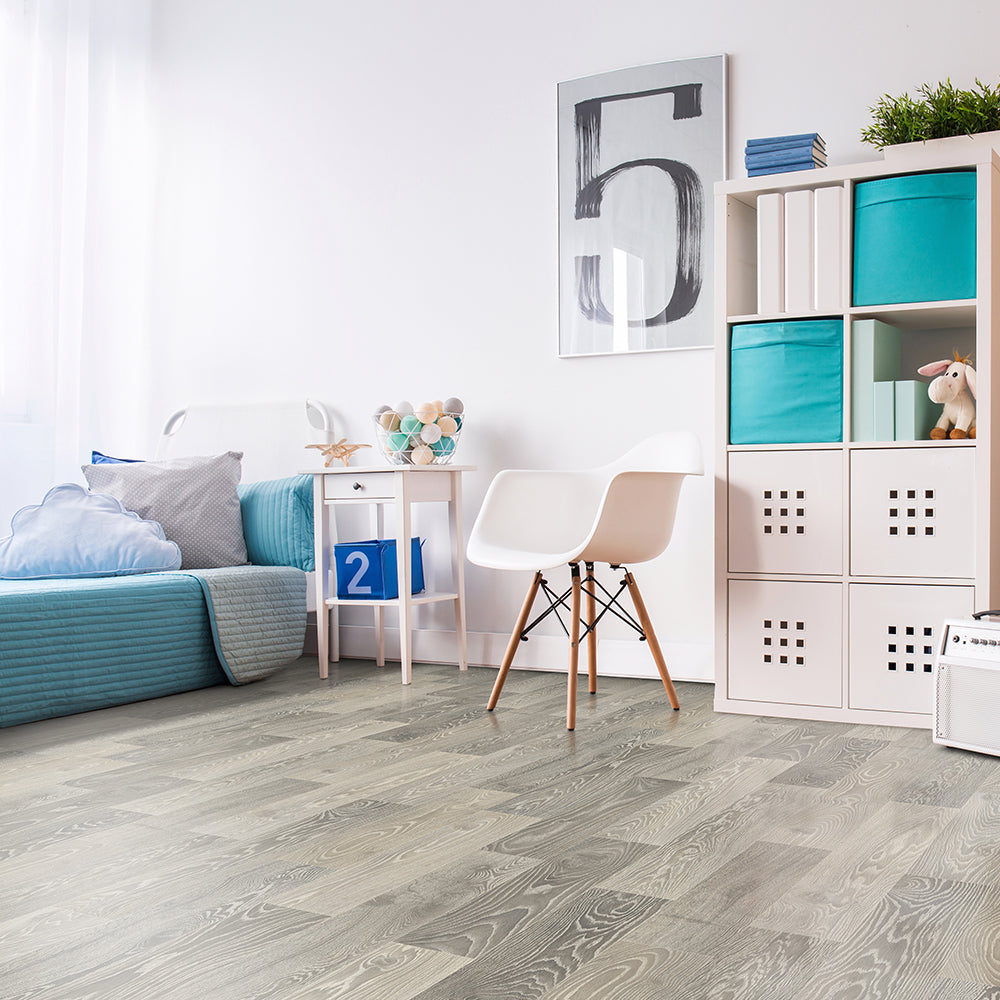 Modern living room with gray wooden flooring, white chair, and colorful bookshelf.