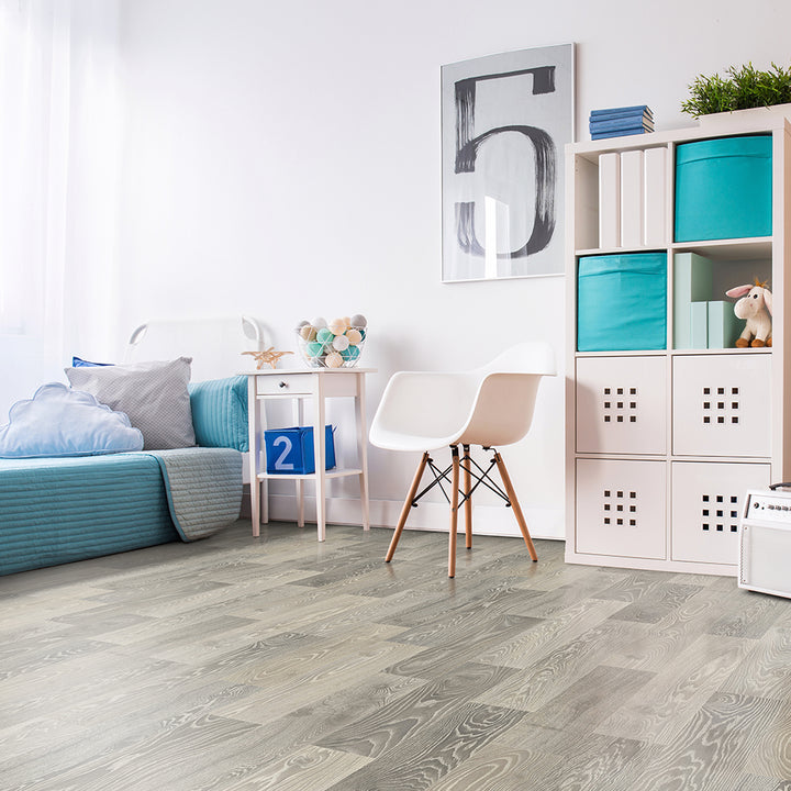 Modern living room with gray wooden flooring, white chair, and colorful bookshelf.