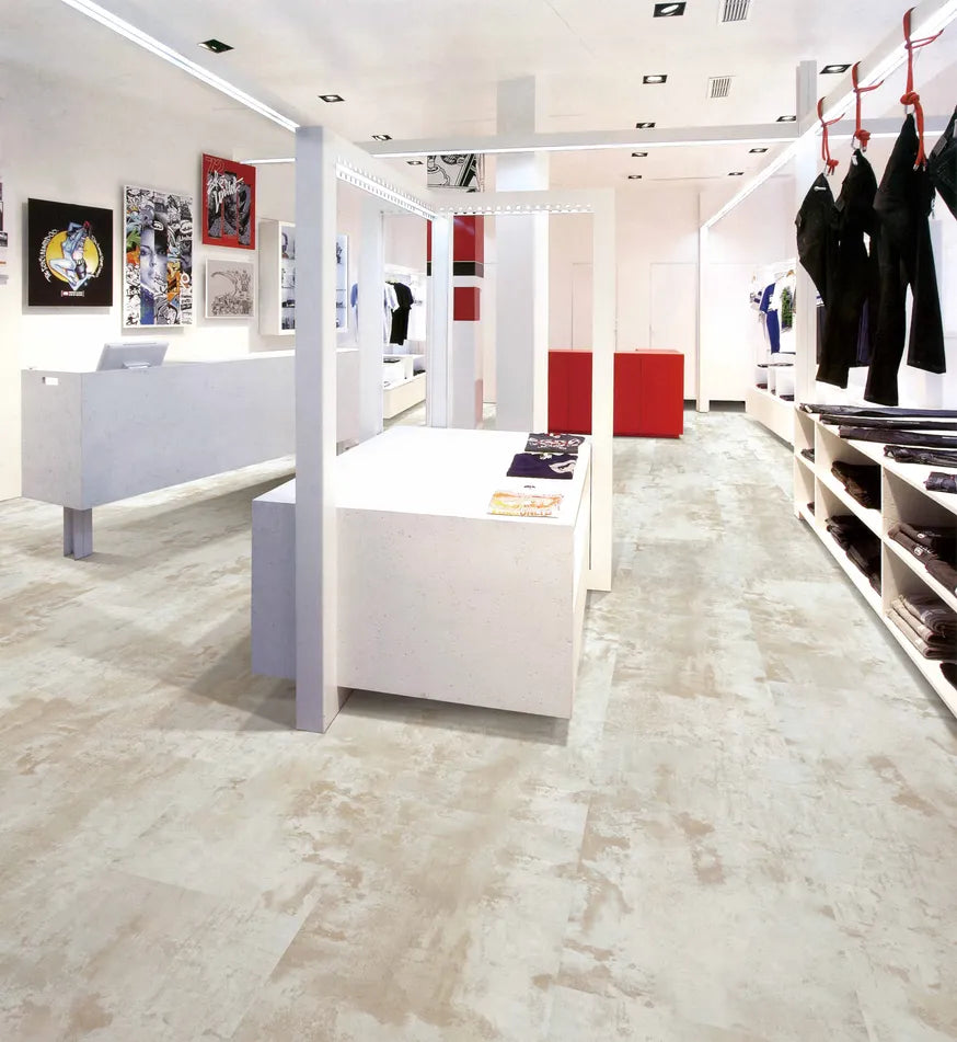 Modern clothing store interior with white display tables and red accents.