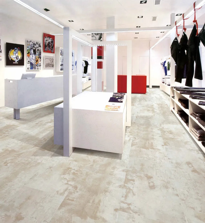 Modern clothing store interior with white display tables and red accents.