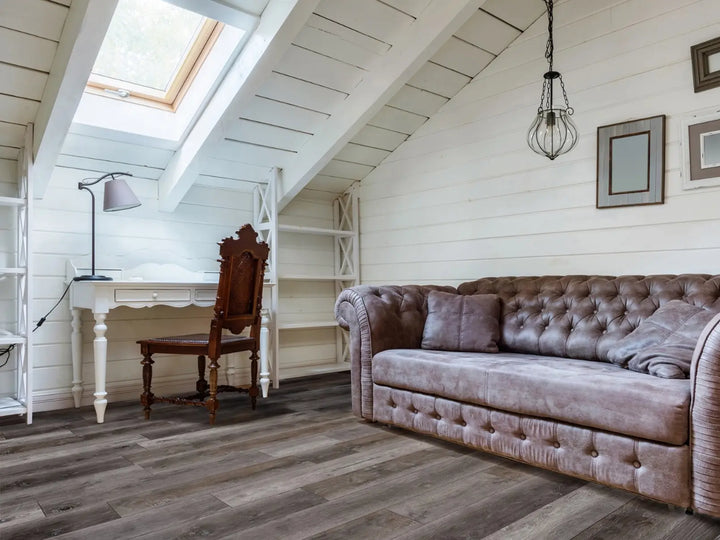 Cozy living room with a brown sofa, wooden chair, and skylight.