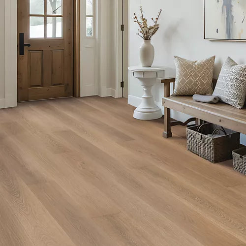 Light oak wood flooring shown in a bright, modern entryway with a wooden bench, white side table, and a wooden door.