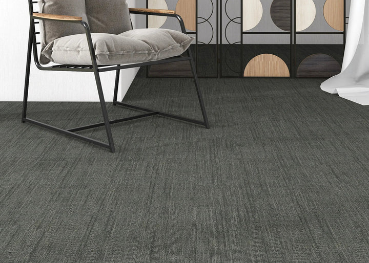 Gray carpeted floor with a chair and decorative elements in the background