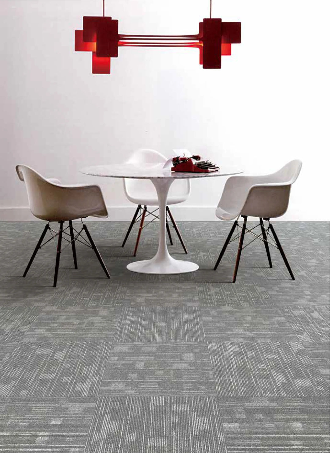Modern dining area with a round table and chairs on a gray patterned carpet.