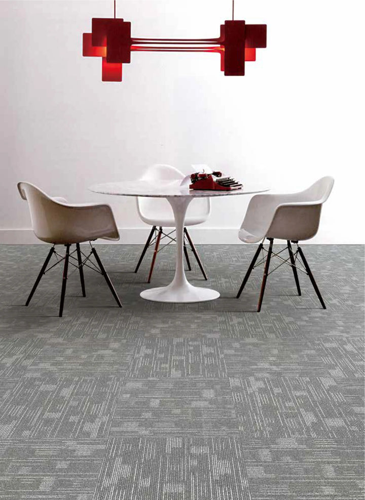 Modern dining area with a round table and chairs on a gray patterned carpet.