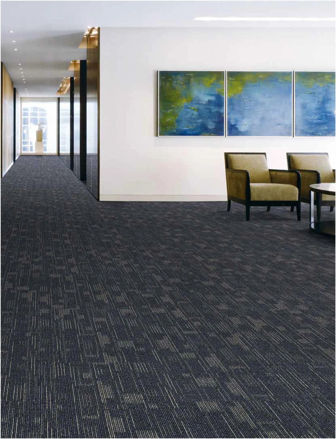 Modern office interior with dark patterned carpet, chairs, and abstract paintings on the wall.