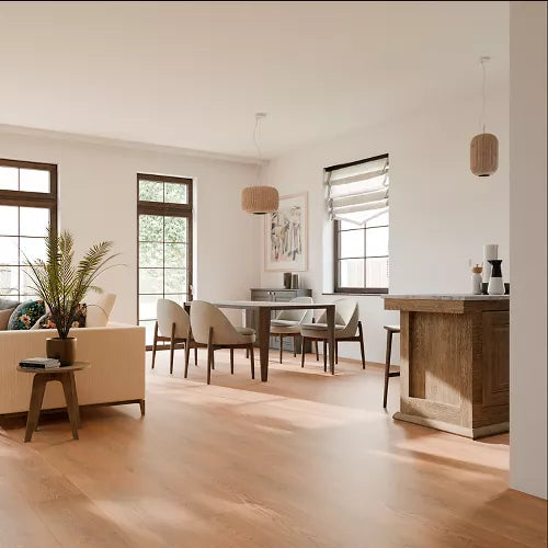 A bright, modern open-concept living and dining room with light oak hardwood flooring, white walls, a beige sofa, a wooden dining table with chairs, pendant lights, and a wooden island bar.