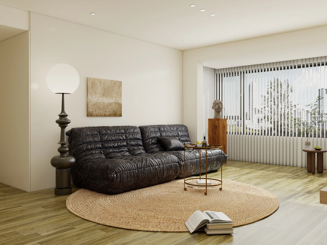 Modern living room with a black leather sofa, round rug, and decorative items.